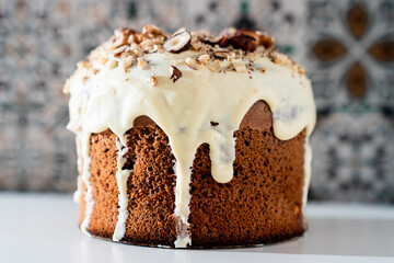 A cake with white chocolate glaze and nuts on a light background. Easter dinner, traditional dishes