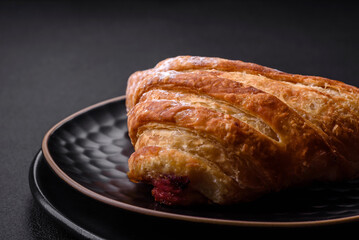 Delicious fresh crispy bun with jam on a black ceramic plate