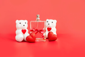 perfume bottles with gift ribbon next to souvenir hearts and polar bear teddy bear toy on red background. Gift card for Valentine's Day. presentation of perfum. declaration of love