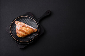 Delicious fresh crispy bun with jam on a black ceramic plate