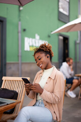happy young woman using a mobile phone and earphones to make a call outdoor in the city