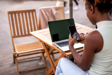 Young woman crossing street and listening to music on headphones in the city