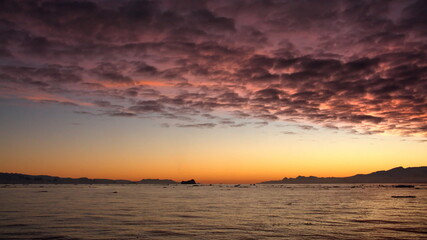 Pink popcorn clouds in an orange sky at sunset, at Cierva Cove, Antarctica