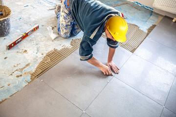 Tiler lays stoneware tiles on the floor