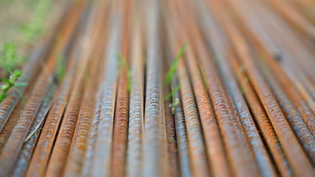 Rusty metal rebar with sprouted grass close-up. Smooth camera movement along metal reinforcement in corrosion