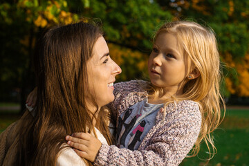 Young woman and child girl joyfully hugging in the park