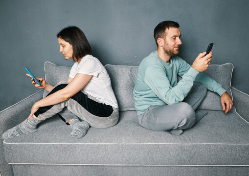 Bored young couple sitting on couch and looking at their smart phones