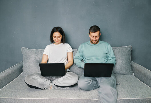 Young couple working on their laptop computer sitting on couch at home