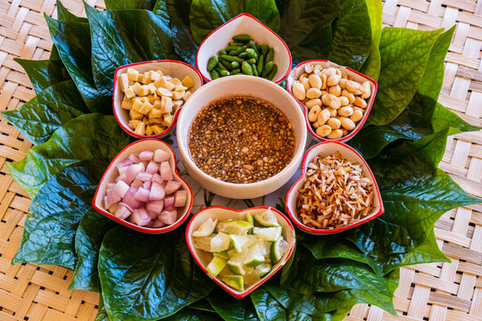 "Miang Kham" is a tasty snack often sold as Thailand street food.It involves wrapping little tidbits of several items in a leaf, along with a sweet-and-salty sauce.Savoury Leaf Wraps