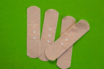 Group of first aid plasters isolated on green background. Top view.