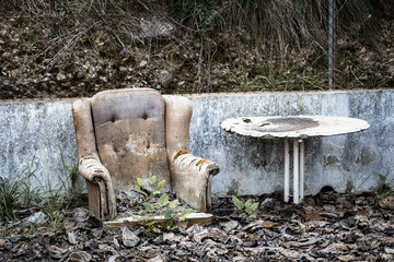 abandoned armchair next to rotten table