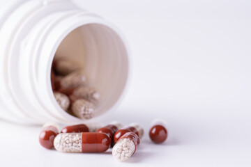 Pills spilling out of pill bottle on white