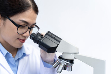 Young female scientist in white laboratory coat working with a microscope in modern laboratory