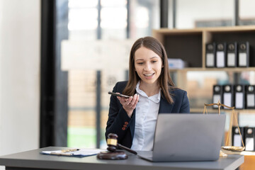 Young beautiful woman lawyer who working in the office. Tlaking on a smart phone with client.