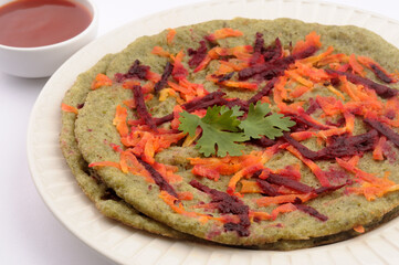 green dosa or pesarattu a south Indian breakfast, grated beetroot and carrot garnished on top