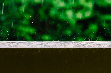 Cinematic shot of raindrops falling from the grey skies and onto the wet surface of a balcony railing, creating ripples in the still water