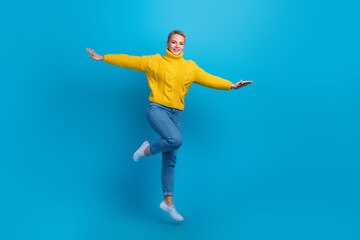Fototapeta na wymiar Full length size photo of excited energetic jumping air flying young woman wear knit pullover hands wings traveler isolated on blue color background