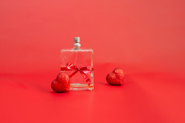 perfume bottle tied with a red festive ribbon among red hearts on a red background,selective focus....