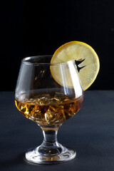 There is a glass of cognac on the table. On which is a slice of lemon.