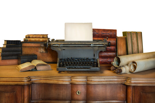 Old wooden desk with vintage typewriter holding an empty sheet of paper and ancient books and maps