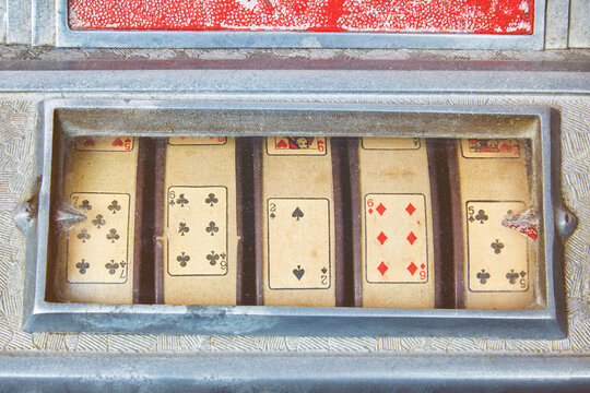 Retro styled image of a close up of a weathered vintage slot machine with playing cards