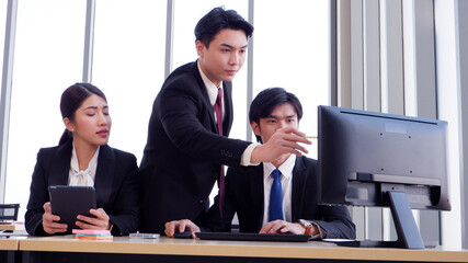Managers and employees working at desks using laptops to work.
