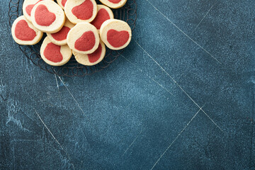 Valentines day cookies. Shortbread cookies inside a sweet red heart on parchment paper on dark blue background. Mothers day. Womans day. Sweet holidays baking. Top view.