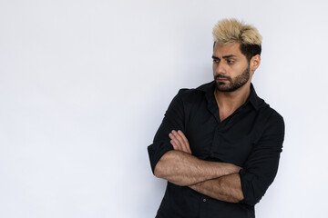 Obraz premium Displeased young man looking at copyspace. Male Caucasian model with brown eyes, ombre painted hair and beard in black shirt crossing his hand looking aside. Advertisement concept