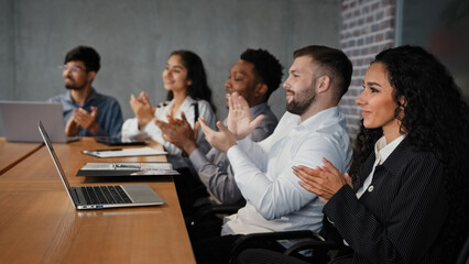 Diverse multiracial business team partners colleagues workers businesswomen and businessmen employees in conference room listen project presentation clap hands in meeting applauding corporate success
