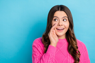 Fototapeta premium Photo of young excited schoolgirl teen aged lady wear pink knitted sweater talk rumor touch cheek look empty space isolated on blue color background