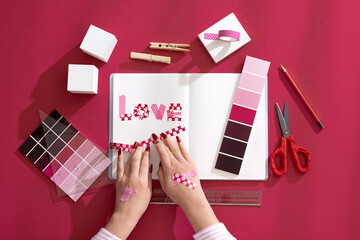 Obraz premium A woman's hand decorating a diary with backgrounds and props composed of Viva Magenta color