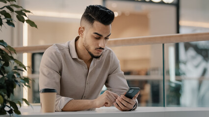 Indian Hispanic man typing smartphone scrolling social media male businessman online message...