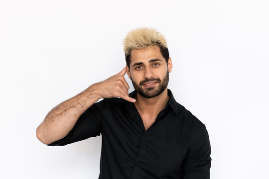 Portrait of winsome young man making phone gesture. Male Caucasian model with brown eyes, ombre painted hair and beard in black shirt showing call me back sign. Coquetry, advertisement concept