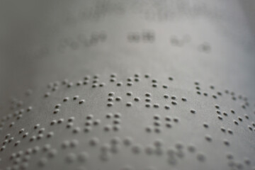tactile braille type on white page of book for blind people - macro photography
