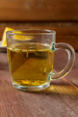 Transparent mug of lemongrass tea on a dark wooden table.
