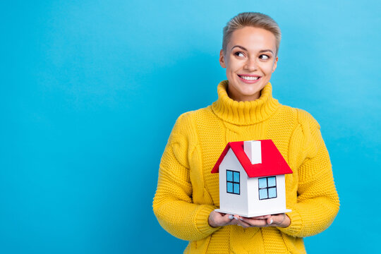 Photo Of Positive New Ownership Cute Blonde Short Hair Girl Wear Yellow Jumper Look Empty Space Hold House No Loan Isolated On Blue Color Background