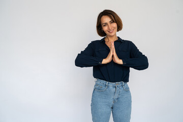 Pleased Caucasian woman pressing hands together. Happy mature female model with short dark hair in navy-blue shirt looking at camera, smiling, asking for something or apologizing. Wish concept