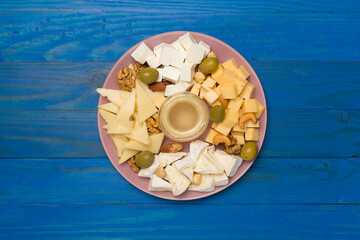 Obraz na płótnie Canvas Cheese plate with olives aand nuts on wooden background, top view