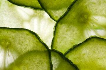 thin slices of cucumber lit from behind, overlapping to form a random pattern.