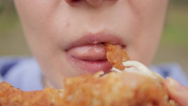 Young woman eating fried chicken. Fast food concept. Close up