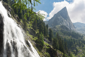 beautiful waterfall in the high tauern massive with the gruebelwand in the background during a beautiful summer hike.
