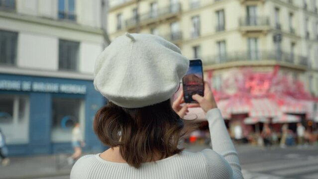 Young woman taking photo with smartphone on french street, slow motion