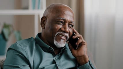 African middle-aged business man senior mature businessman entrepreneur at home in office talking phone chatting mobile conversation booking order with smartphone call discussing remote talk speaking