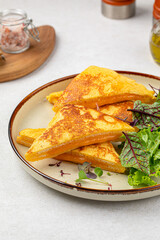 Portion of roast egg toast with cheese and green salad