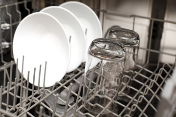 Clean dishes are in the dishwasher. The concept of cleaning dirty dishes and glasses