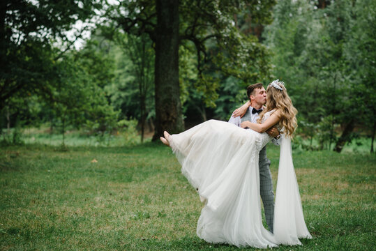 Romantic wedding moment, couple of newlyweds kissing in nature in the park. Wedding ceremony.