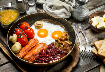 English breakfast.Fried eggs with sausages, bacon and red canned beans.