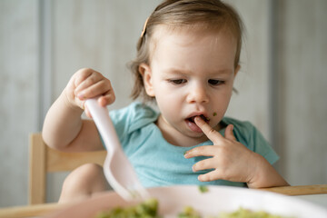 one girl small caucasian child one year old eat at the table at home