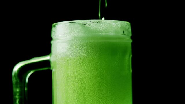 Green beer with foam and bubbles in the pint.