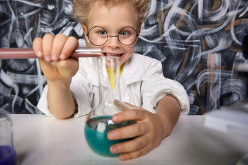 Cute blond boy participates in scientific study and conducts chemical scientific experiment by...